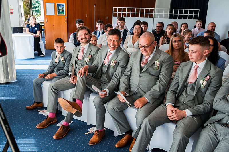 Groomsmen smiling at wedding ceremony.