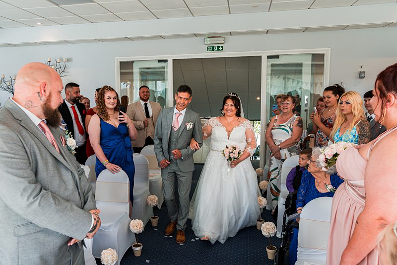 Bride walking down aisle at wedding ceremony.