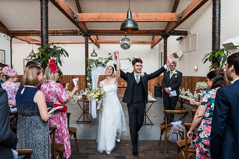 Bride and groom celebrating marriage ceremony indoors.