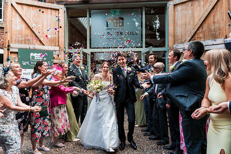 Newlyweds celebrate outside with confetti and guests.