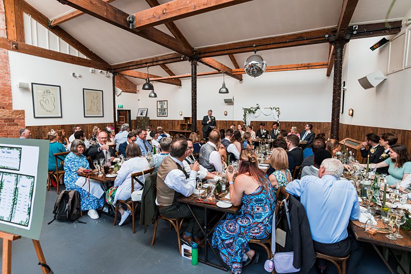 Guests attending a wedding reception inside rustic venue.