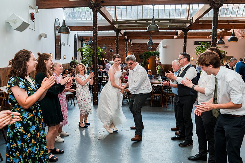 Wedding guests dance and clap in celebration.