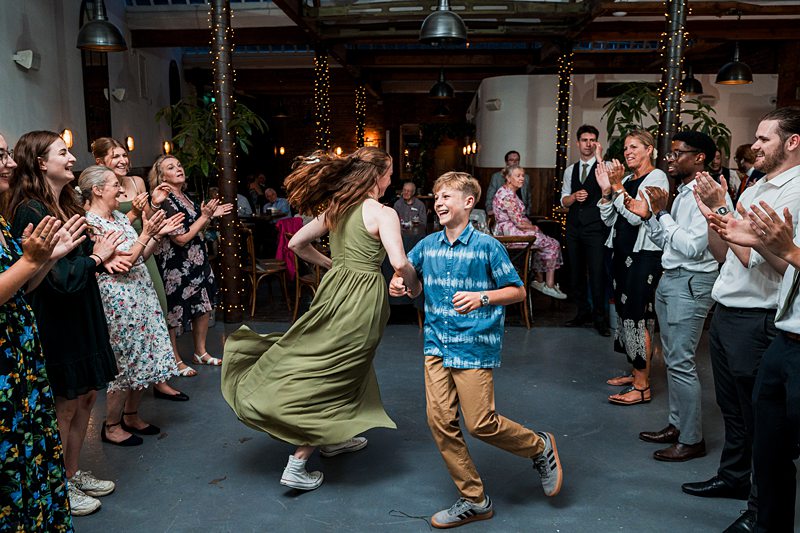 Guests joyfully dance at lively wedding reception.