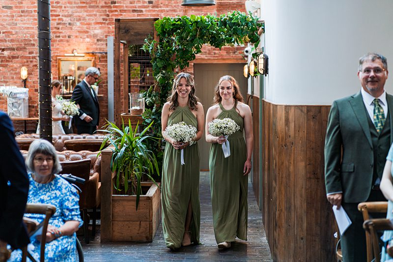 Bridesmaids in green dresses at wedding ceremony.