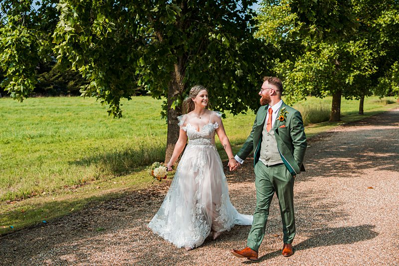 Bride and groom walking outdoors, holding hands.
