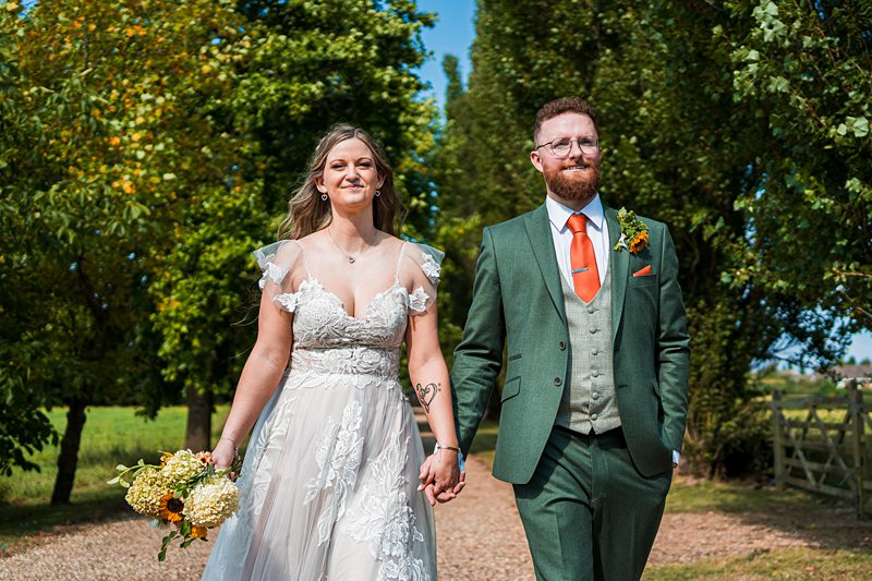 Bride and groom walking outdoors, holding hands.