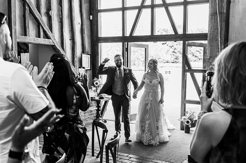 Couple enters wedding ceremony to applause.