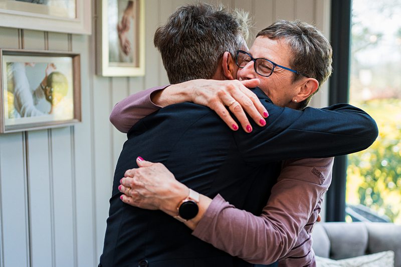 Two people embrace warmly in living room.