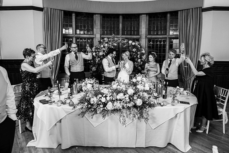 Wedding toast with friends around decorated table.