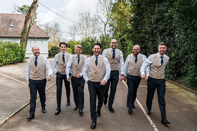 Groomsmen walking outdoors in matching suits.