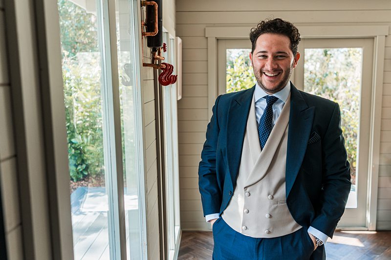 Man smiling in formal three-piece suit indoors.