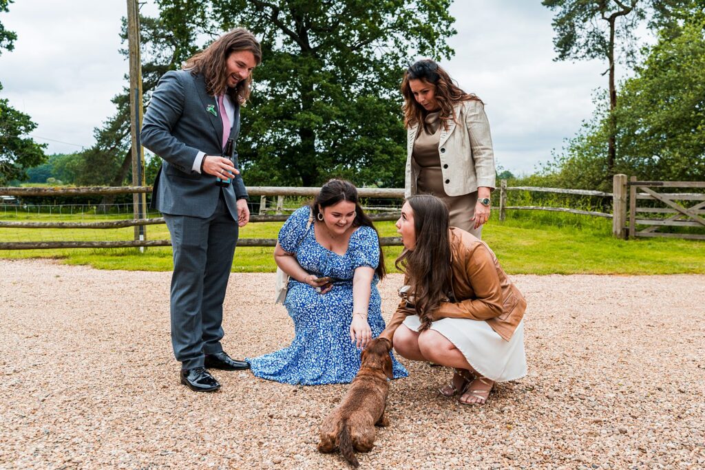 People petting a dachshund outdoors.