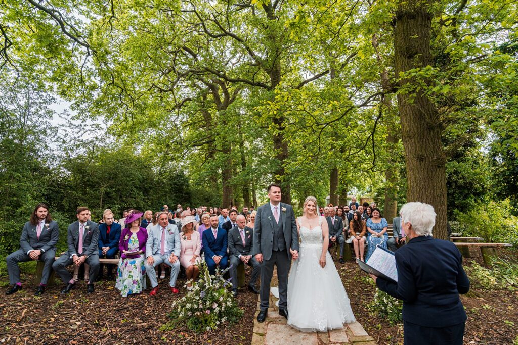 Outdoor wedding ceremony with couple and guests seated.