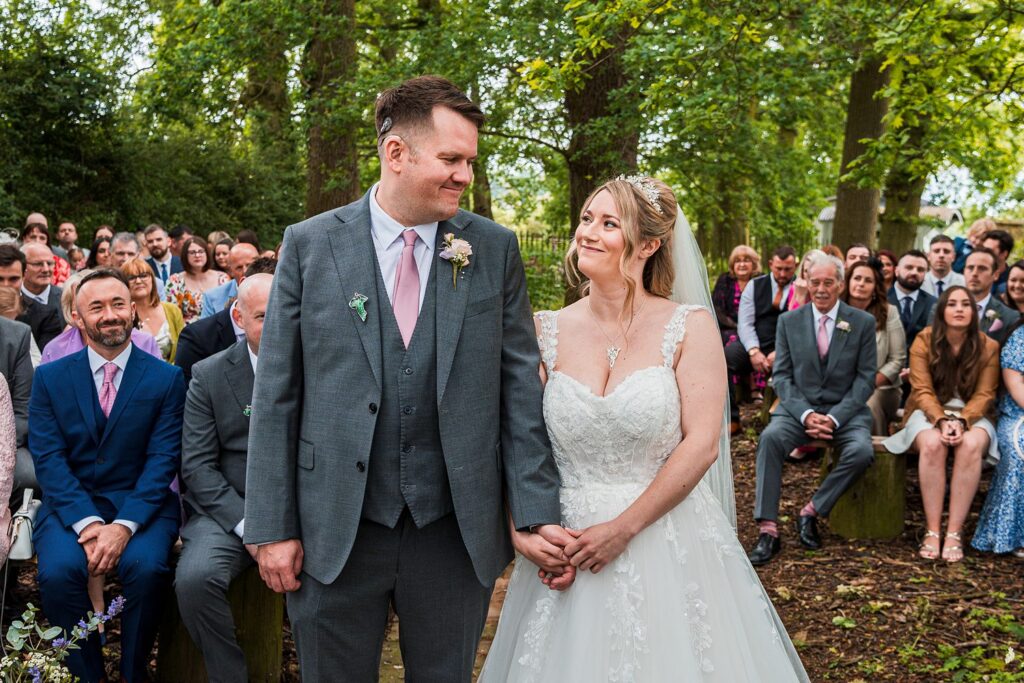 Outdoor wedding ceremony with bride and groom smiling.