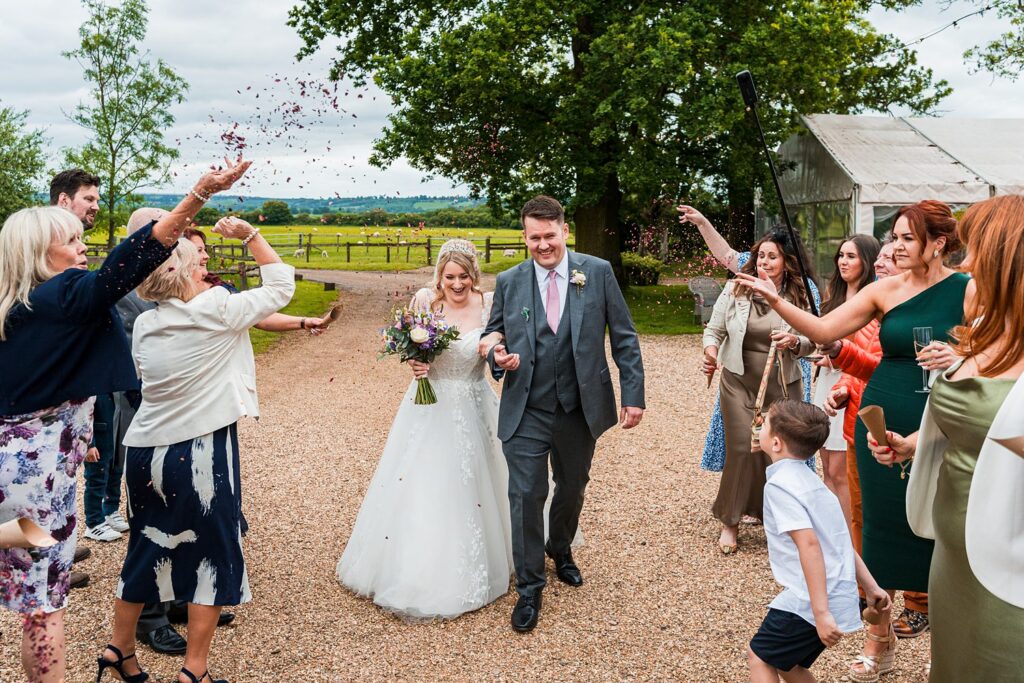 Bride and groom with confetti at outdoor wedding.