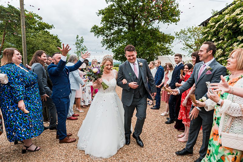 Newlyweds leaving church, guests throwing confetti.