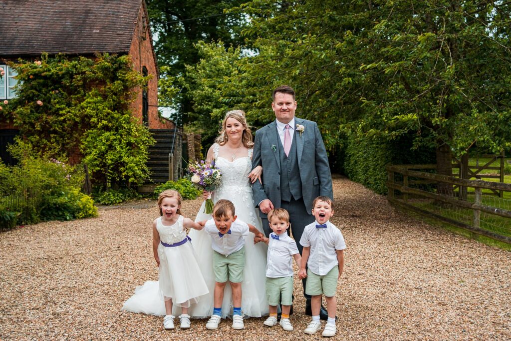 Bride and groom with children outside rustic venue