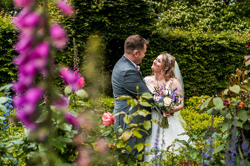 Bride and groom smiling in garden wedding.