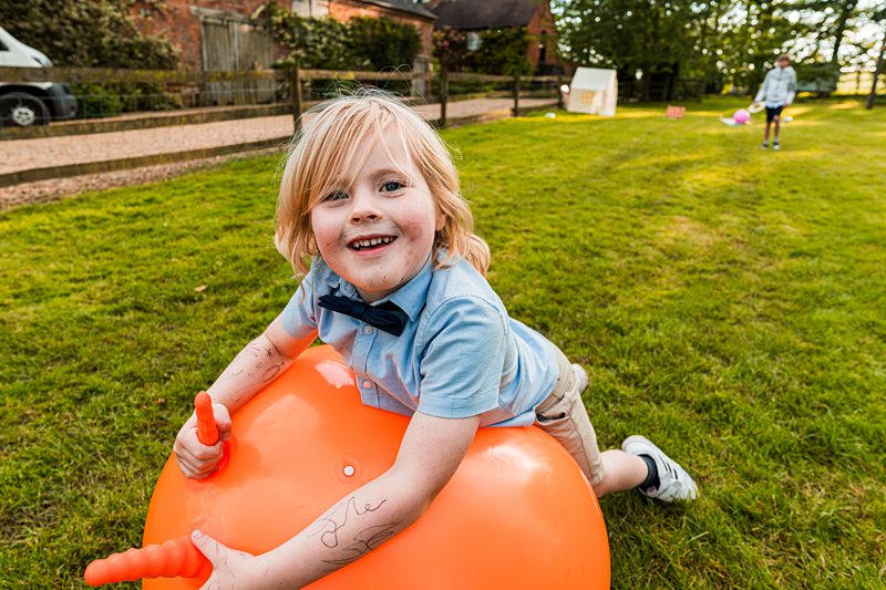 Child playing with orange space hopper in garden.