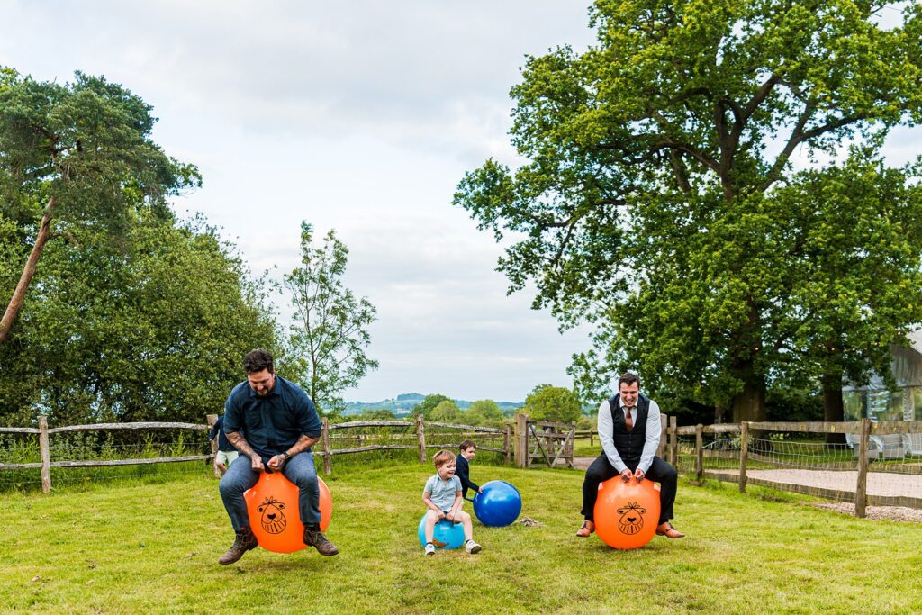 People bouncing on space hoppers in a garden.