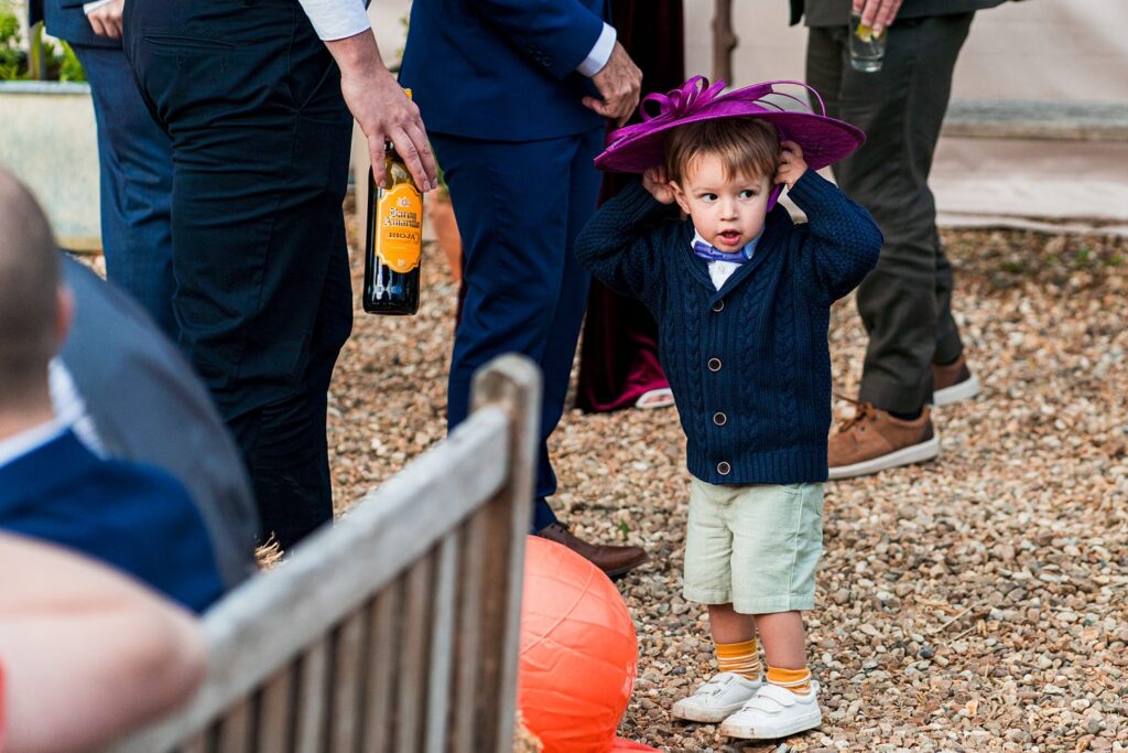 Child wearing oversized hat at outdoor gathering