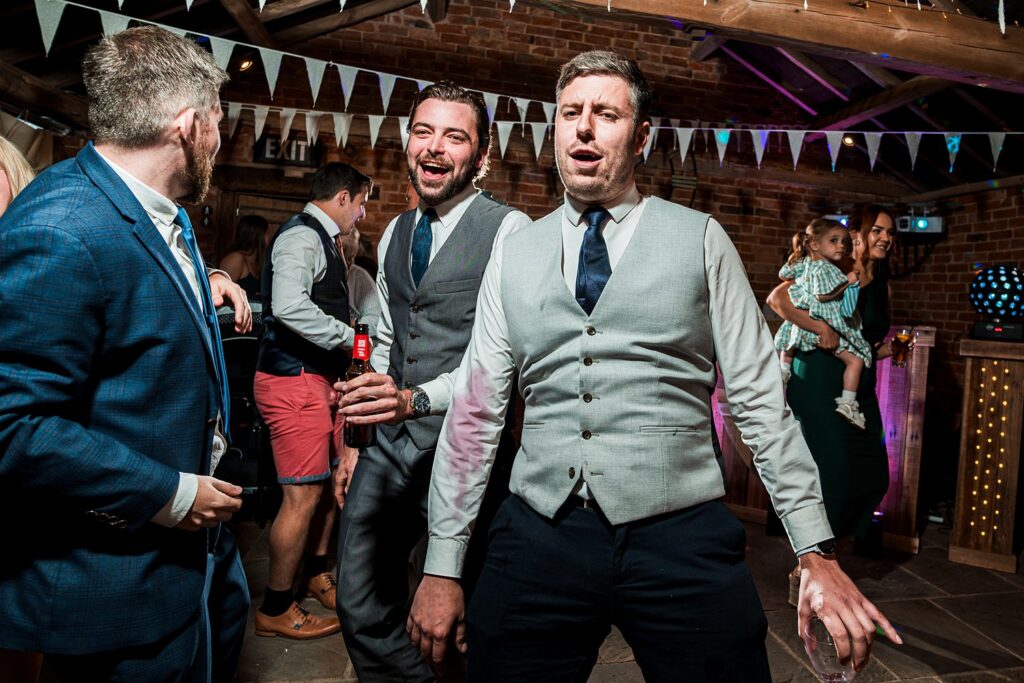 Men in suits dancing at a lively wedding party.