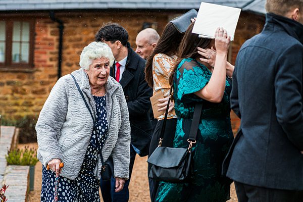 Elderly woman walking near group at outdoor event.