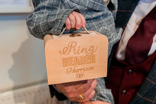 Child holding wooden ring bearer box.
