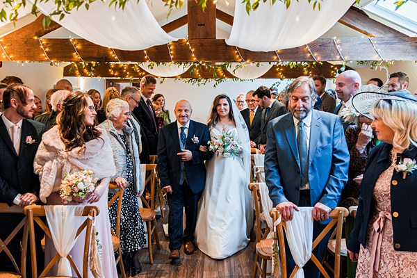 Bride walking down the aisle with guests watching.