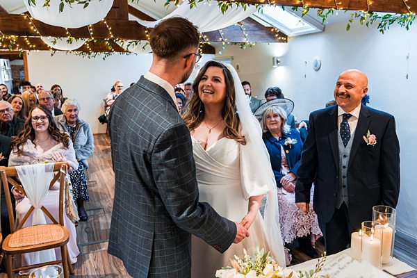 Couple exchanging vows at wedding ceremony, smiling guests.