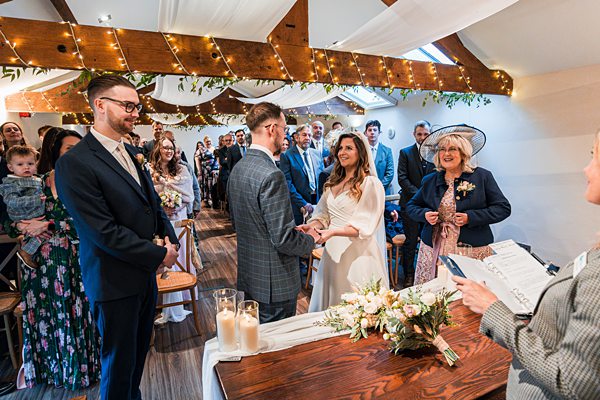 Bride and groom exchanging vows at indoor ceremony.