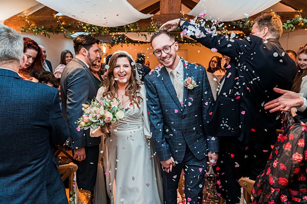 Happy couple exiting wedding ceremony with confetti shower.
