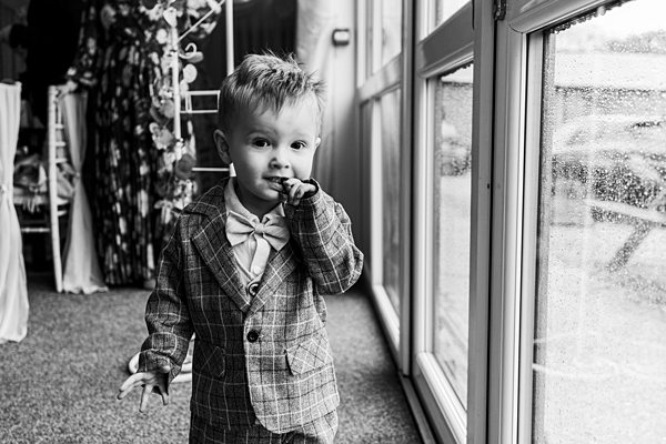 Child in suit near window, black and white photo.