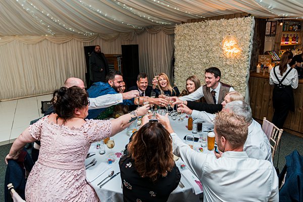 Friends toasting at a wedding reception dinner table.