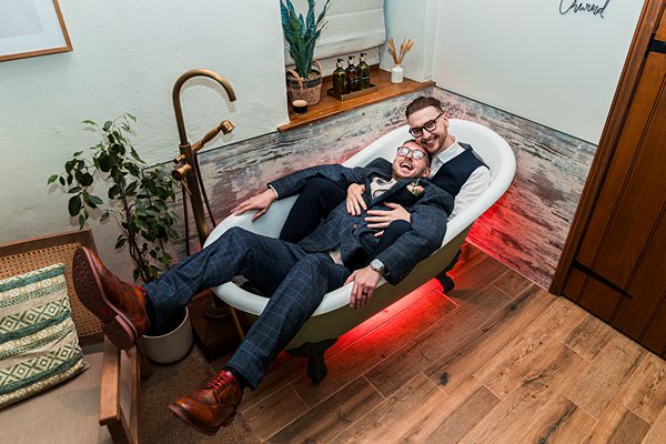 Two people in suits relaxing in a bathtub.
