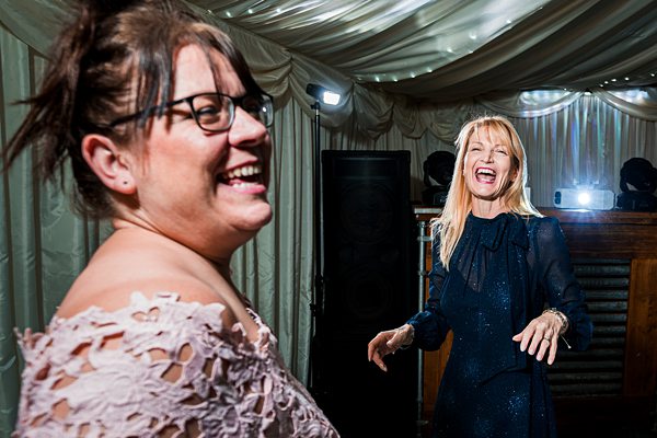 Two women laughing and dancing at a party.