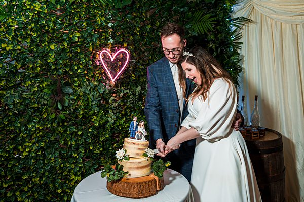 Bride and groom cutting wedding cake together.