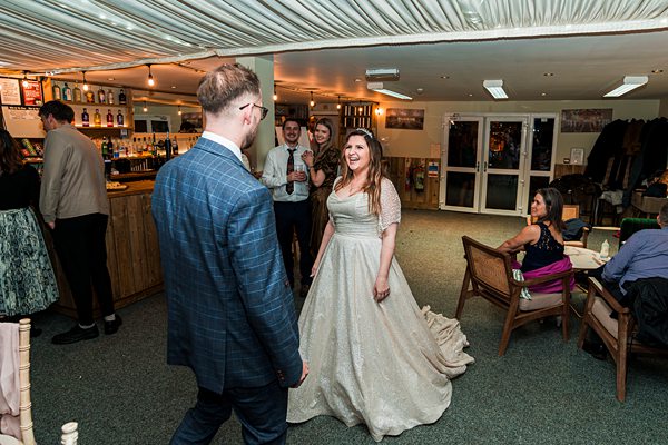 Bride smiling at wedding reception with guests.