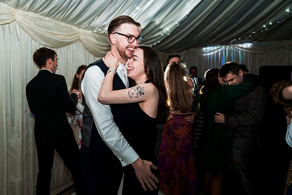 Couple dancing at wedding reception under marquee lights.