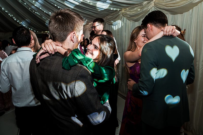 Couples dancing at a wedding under heart lights.