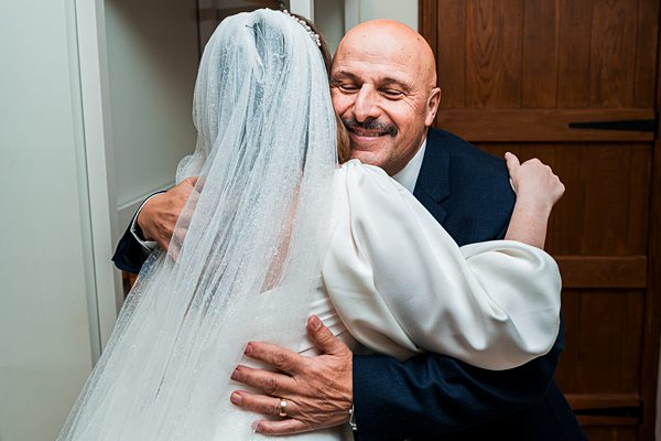 Bride and man embracing warmly, wedding celebration scene.