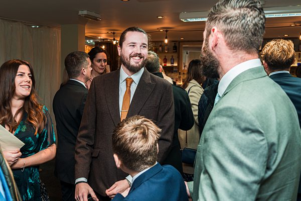 People socialising at an indoor event, wearing formal attire.