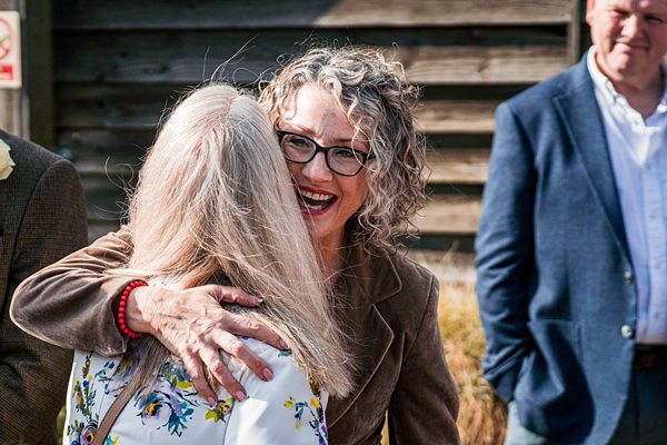 Two women embracing outdoors, smiling warmly.
