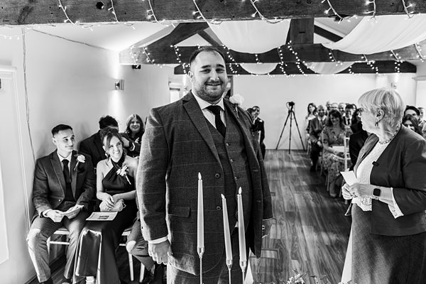 Groom smiling in wedding ceremony room.
