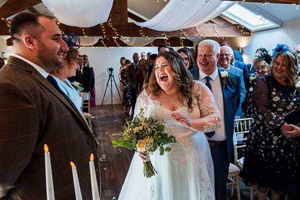 Bride laughing during wedding ceremony with guests.