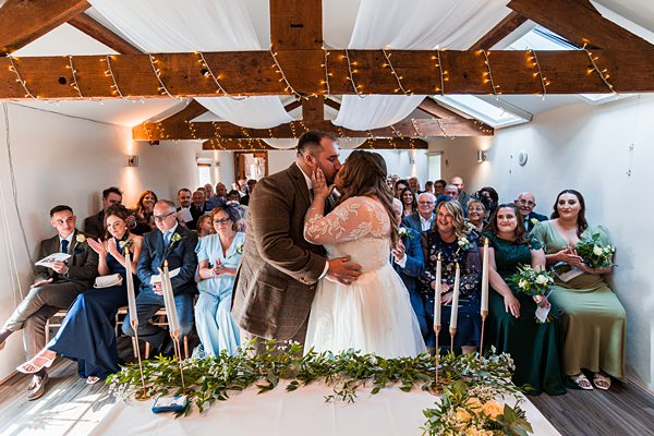 Bride and groom kissing at wedding ceremony.