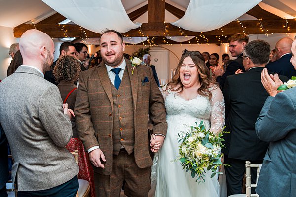 Bride and groom walking down the aisle, smiling.