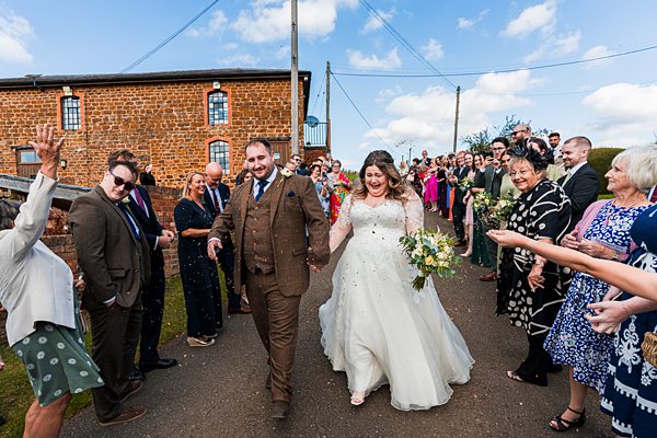 Just married couple leaving wedding celebration, smiling guests.