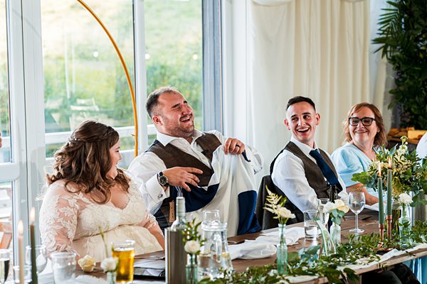 Wedding guests laughing during reception speech.