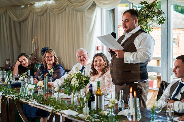 Wedding speech at reception with laughing guests.